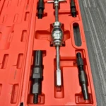 Extractor de rodamientos interno de 5 piezas en caja naranja con herramientas metálicas y accesorios negros dispuestos en compartimentos.