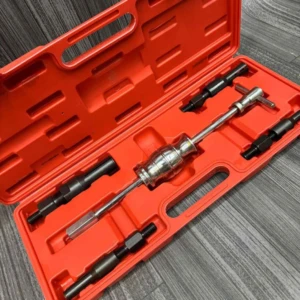 Caja naranja abierta con extractor de rodamientos interno de 5 piezas, incluyendo herramienta central metálica y accesorios negros, sobre superficie gris texturizada.