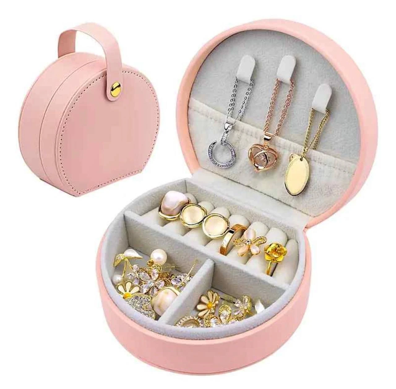 Joyero circular rosa con asa, abierto para mostrar compartimentos organizadores de anillos, collares y aretes. Incluye tres ganchos para colgar cadenas en la tapa interior.
