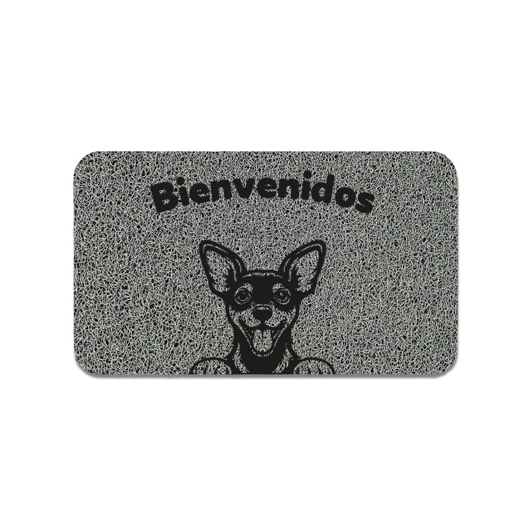 Tapete de entrada rectangular en tono gris con textura granulada, muestra un perro de orejas erguidas y lengua afuera, acompañado del texto “Bienvenidos” en la parte superior.