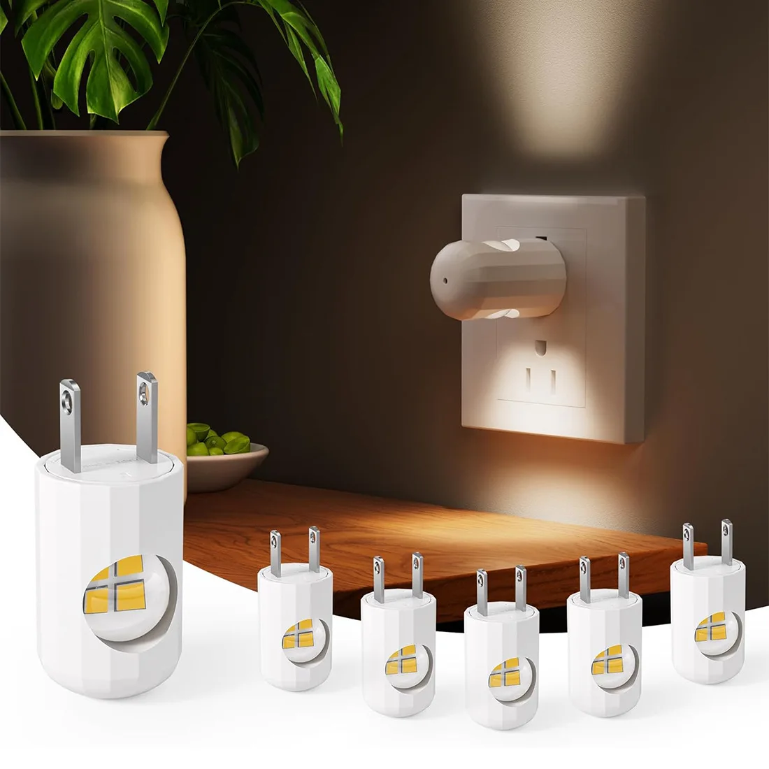 Cinco cargadores LED blancos con luz cálida, uno en uso en pared y cuatro adicionales sobre mesa de madera, junto a maceta con planta.