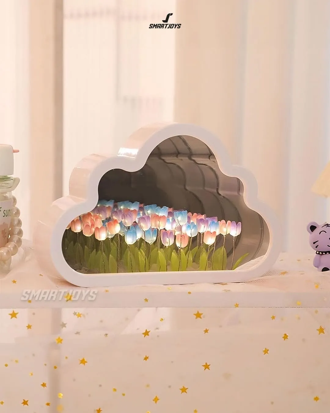 Lámpara espejo en forma de nube con jardín de tulipanes multicolores y luz LED, sobre estante decorado con estrellas doradas.