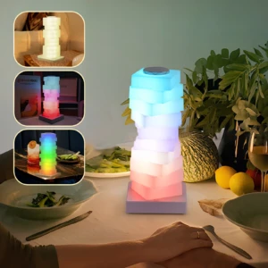 Lámpara LED RGB modular con bloques apilables en tonos azul, blanco y rosa, sobre mesa de comedor con platos y frutas.