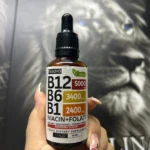 Frasco de vidrio ámbar con gotero de 50 ml y etiqueta blanca de Nusava B12, B6 y B1 con niacina y folate sabor a frambuesa.