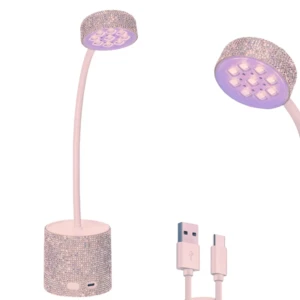 Lámpara UV compacta con base y cabeza decoradas con cristales, cuello flexible en color rosa pálido, incluye cable USB para carga.
