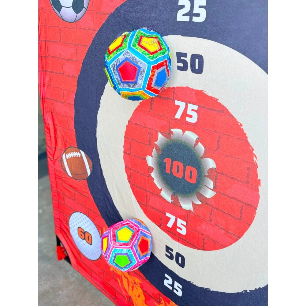 Kit deportivo de puntería con dianas concéntricas numeradas hasta 100, fondo de ladrillo rojo, dos pelotas multicolores impactando en la diana central.