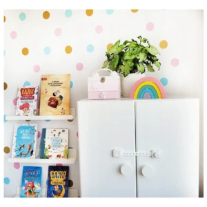 Cerradura de seguridad para niños en color blanco, instalada sobre dos puertas de gabinetes blancos en ambiente infantil con estanterías y decoración.