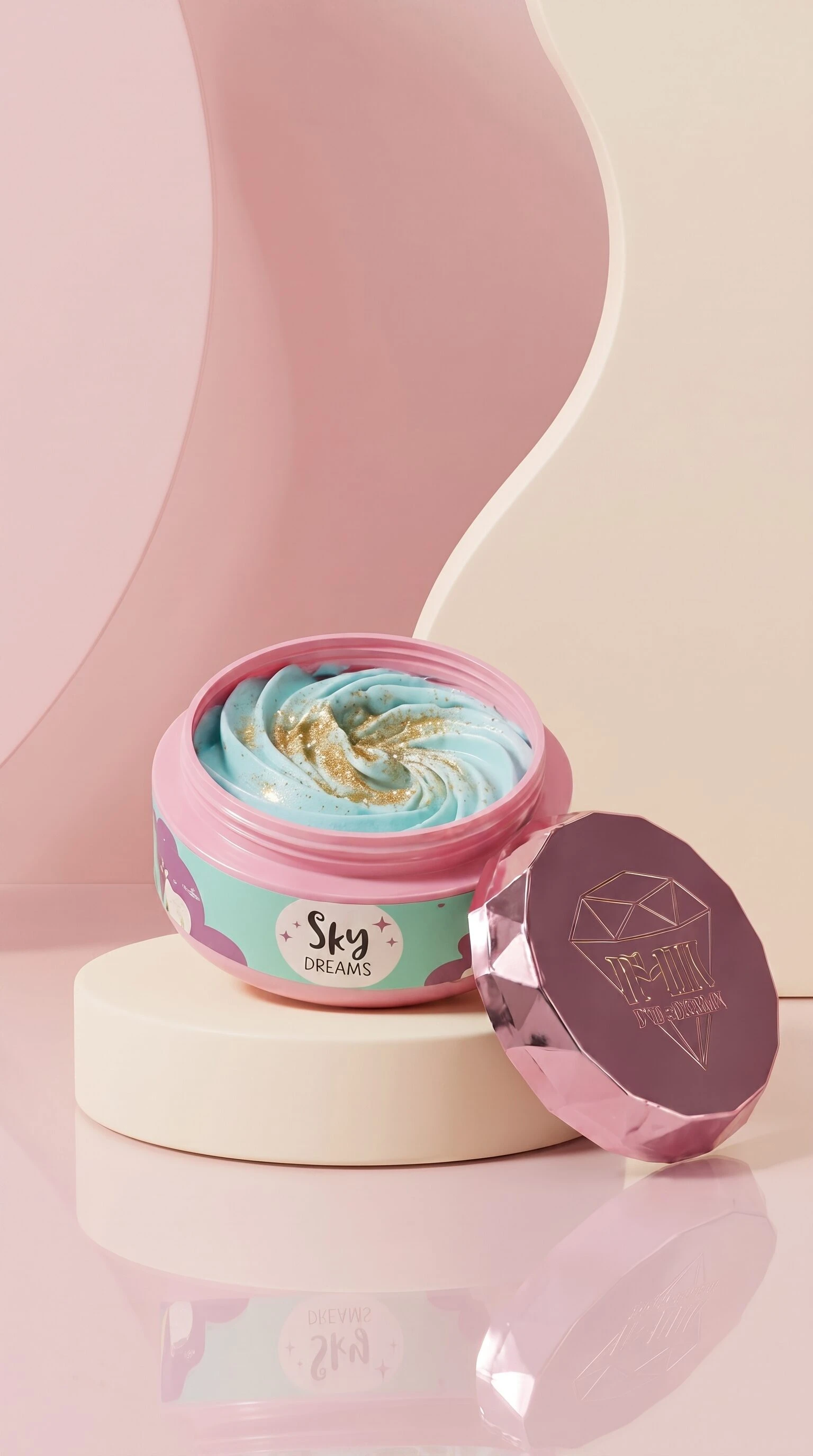 Jarrín cosmético abierto con crema azul y dorada, tapa rosa brillante al lado, sobre pedestal blanco en fondo rosa.