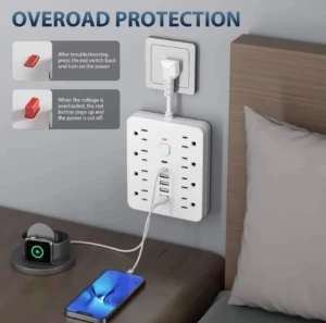 Regleta blanca de pared con 14 tomas, puertos USB y Type C, enchufada en pared gris junto a cabecera de cama; incluye iconos explicativos sobre protección contra sobrecarga.