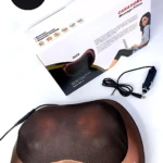 Almohada masajeador de color cobre con superficie texturizada y luces LED, junto a su caja y cable de alimentación.