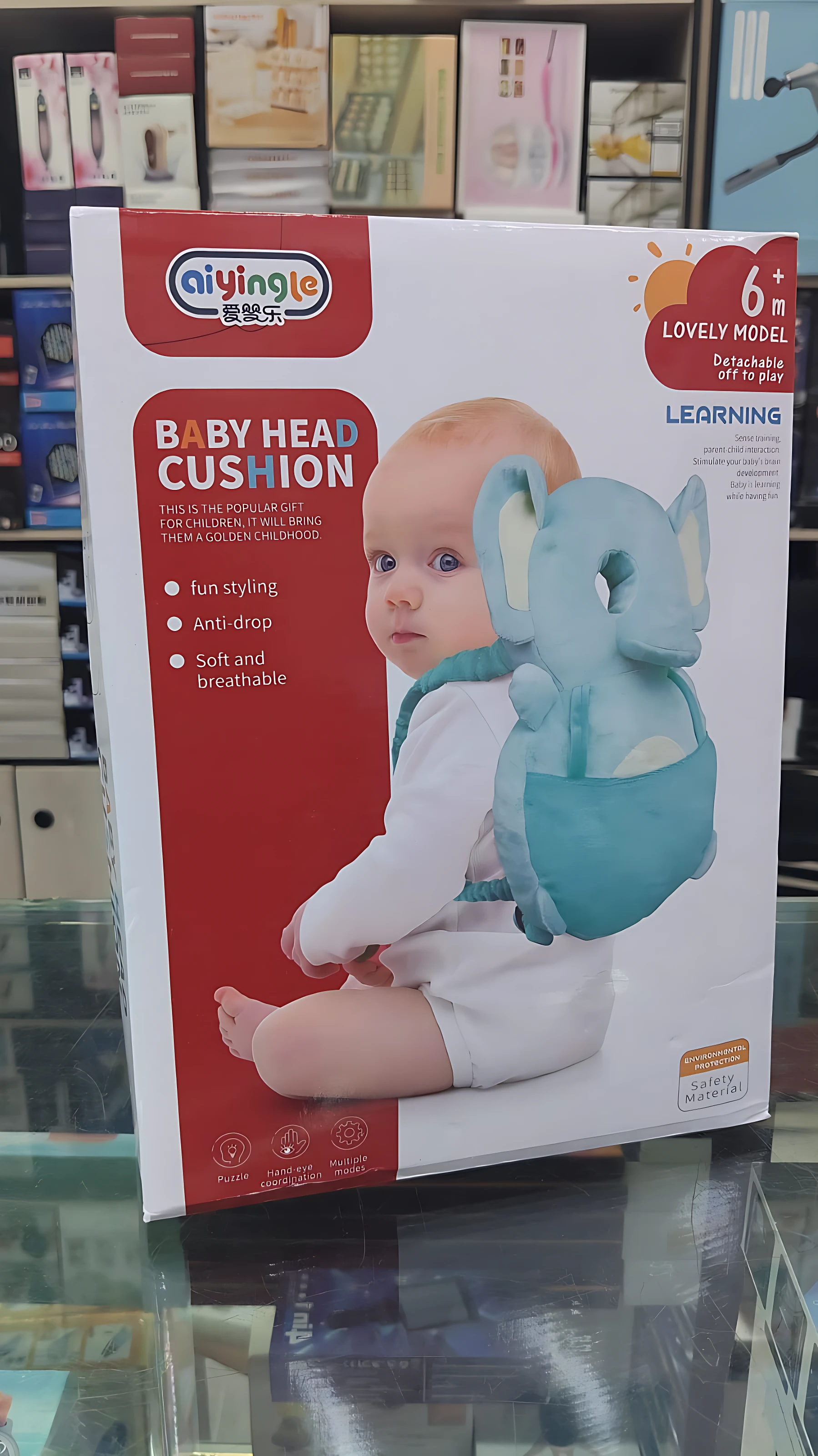 Almohada mochila azul con diseño de elefante para bebé, en caja de presentación con del producto y bebé usando el accesorio.