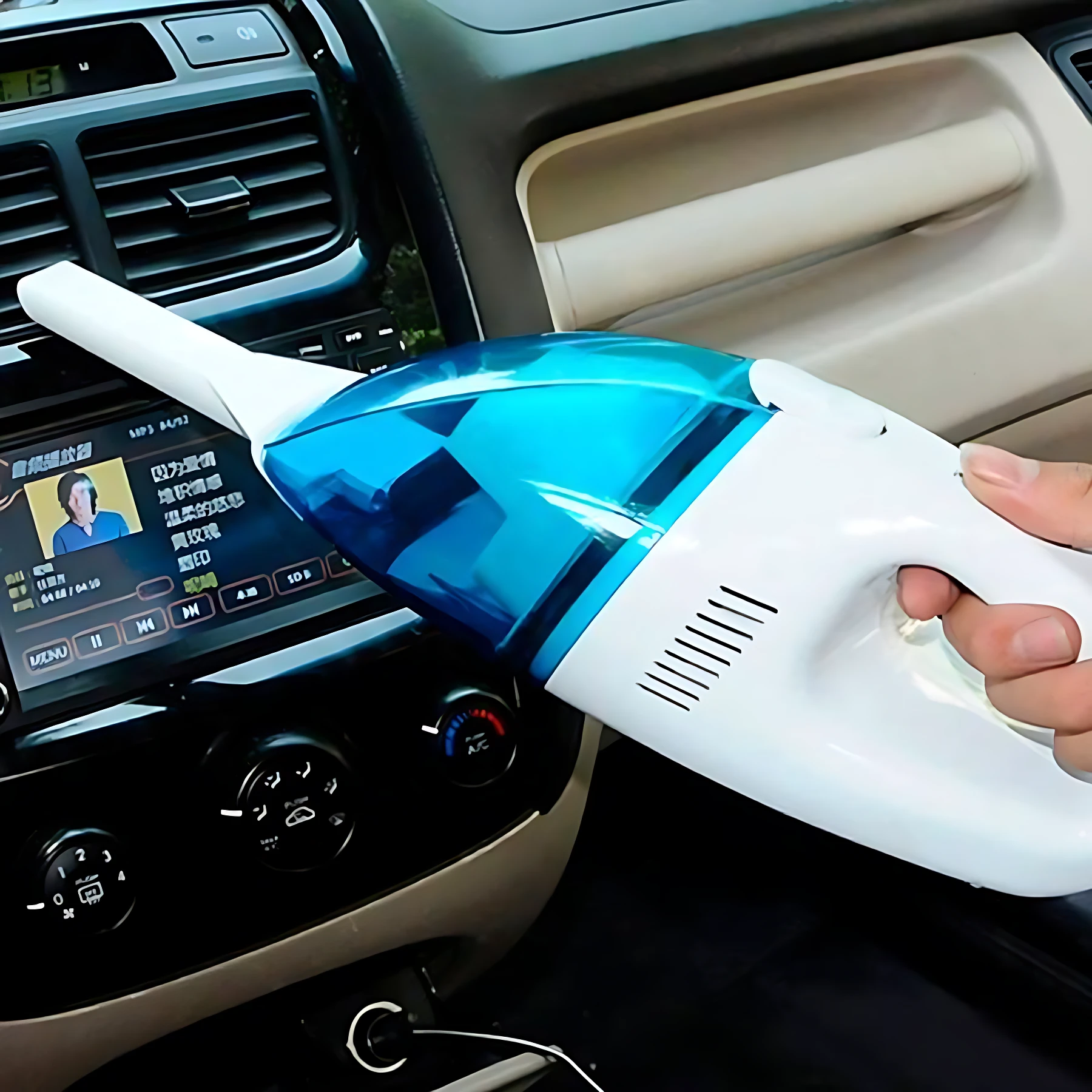 Aspiradora eléctrica para carro en color azul y blanco, con boquilla plana, siendo usada para limpiar el tablero de un vehículo.