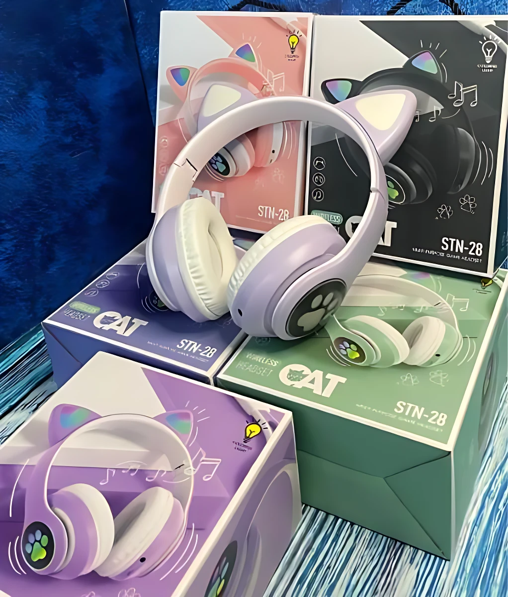 Auriculares diadema color lila con orejas de gato, luces LED y logo de pata. Se muestran sobre sus cajas en tonos pastel, con detalles de música y diseño infantil.