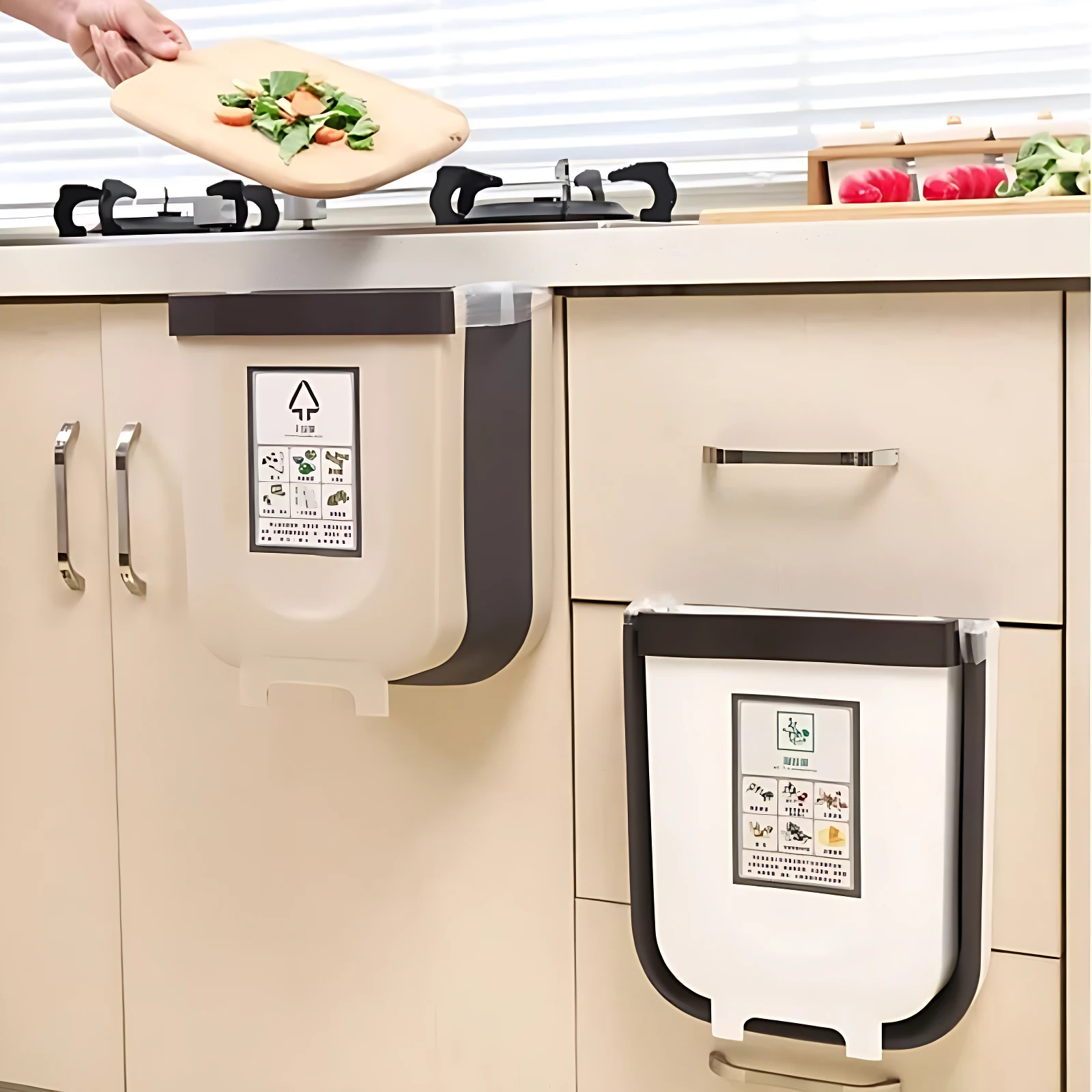 Basurera portátil plegable beige con ganchos negros, montada en armario de cocina; incluye etiqueta de clasificación de residuos y se usa para contener restos de comida.