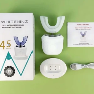 Cepillo dental eléctrico U con cabezal en forma de U, color blanco, junto a su caja, base de carga y cable USB sobre fondo verde.