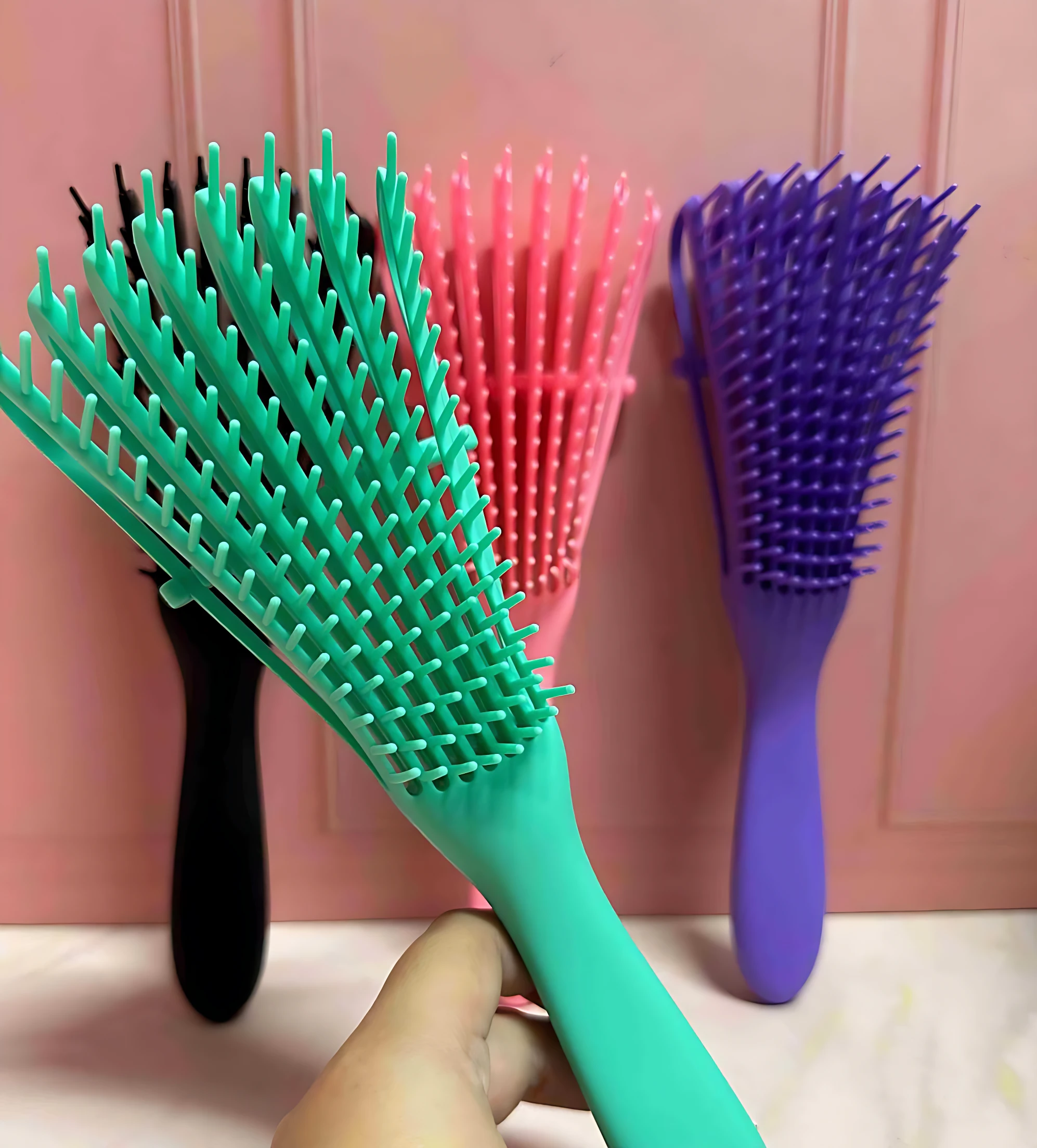 Cepillo desenredante antifrizz con cerdas flexibles en verde menta, rosa y morado, mostrando tres unidades con mango ergonómico y cerdas separadas para eliminar nudos sin dolor.