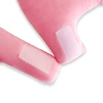 Cojín ergonómico para lactancia en color rosa, con textura suave y parches adhesivos visibles en la superficie.