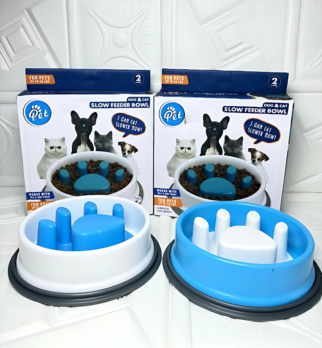 Dos comederos antirreflujo para perros y gatos, uno azul y otro blanco, con base antideslizante. Incluyen caja de presentación y diseño ergonómico para controlar la velocidad de alimentación.