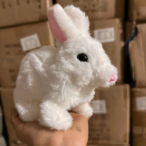 Peluche conejo blanco de pelaje suave, orejas rosadas y nariz rosa, sostenido en la mano; variante individual del set de tres.