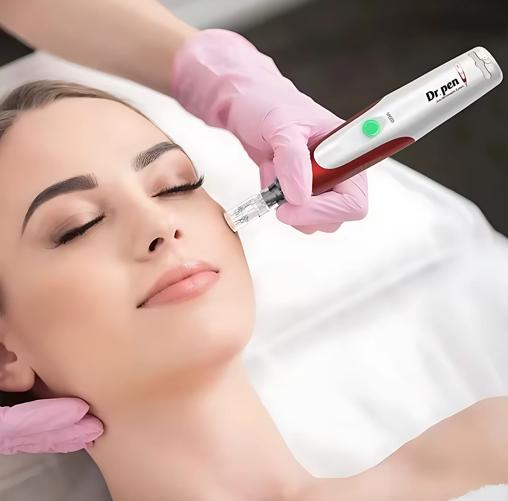 Dr Pen N2 en uso: dispositivo inalámbrico blanco y rojo aplicando tratamiento facial en mujer con guantes rosas.