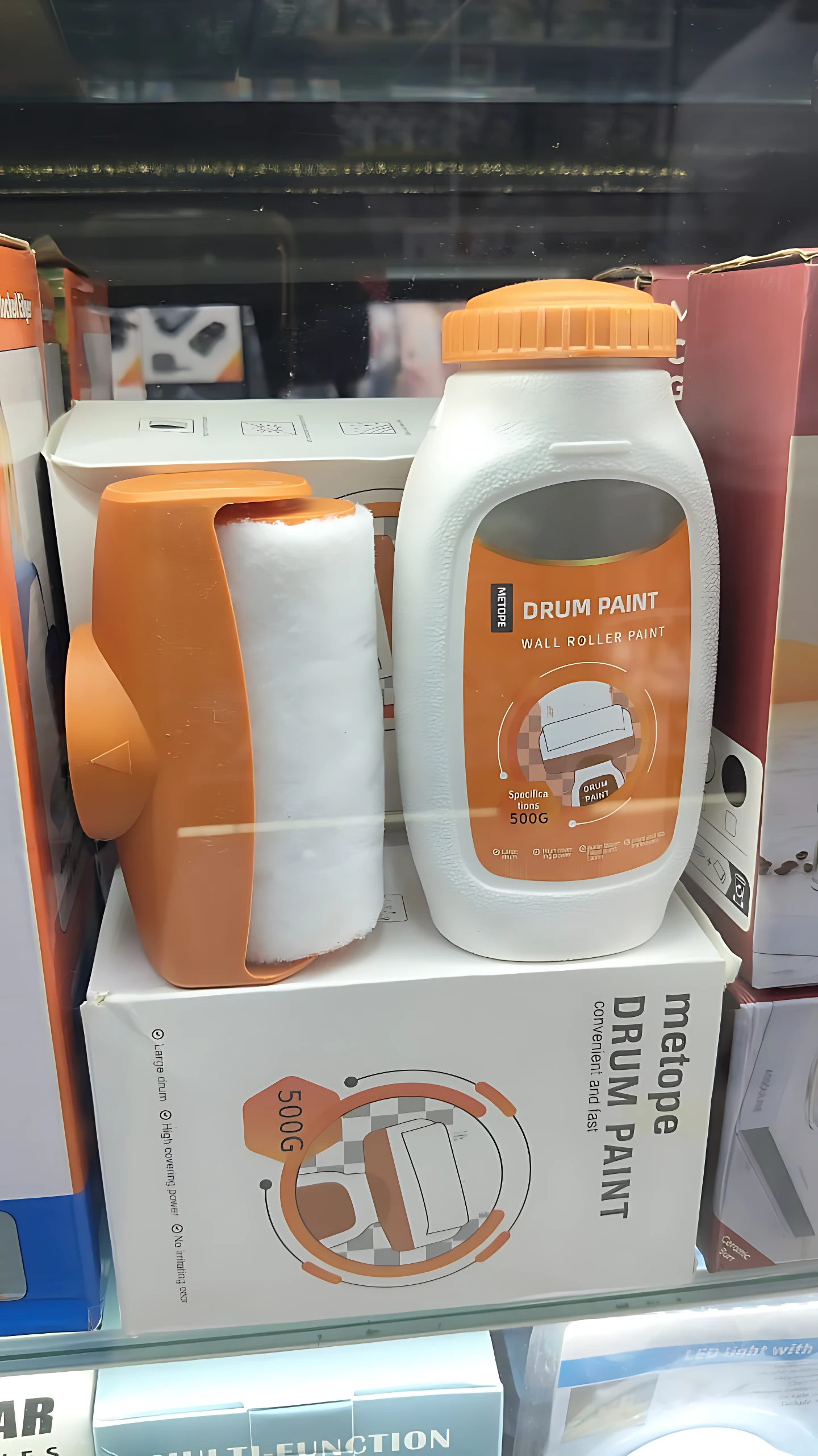Pintura portátil blanca con rodillo naranja integrado, envase de 500 g, ideal para retoques rápidos en paredes.
