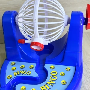 Juego de bingo mecánico manual en color azul, con esfera giratoria blanca y números amarillos, ideal para fiestas y reuniones familiares.