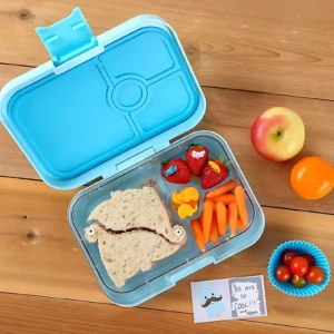 Lonchera azul con compartimentos, incluye sándwich en forma de animal, frutas, zanahorias y nota divertida. Ideal para niños.