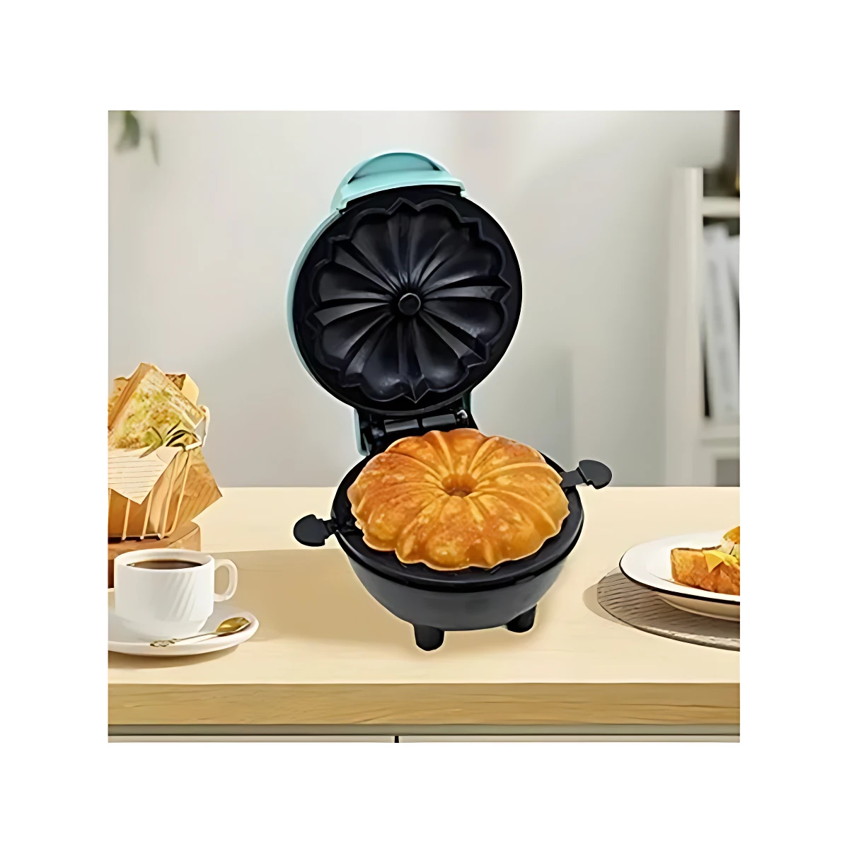 Máquina eléctrica para tortas individuales con forma de anillo, color negro y tapa azul claro, mostrando bizcocho horneado en su molde interior sobre mesa de madera.