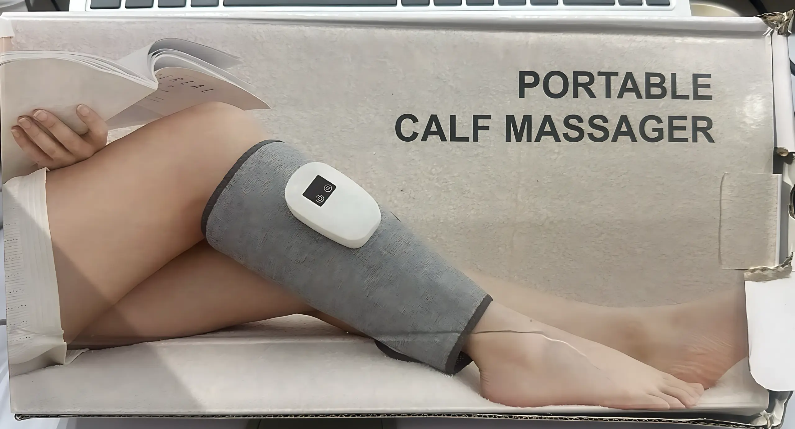 Masajeador de pantorrilla gris con control digital blanco, aplicado en la pierna de una persona relajada, mostrado en el empaque del producto.