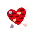 Molde de silicona rojo en forma de corazón con cavidades para chocolates, acompañado de piezas decorativas en tonos pastel.