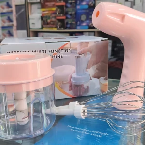Multiprocesador eléctrico rosa con batidor y vaso transparente, sobre mostrador de vidrio en tienda.