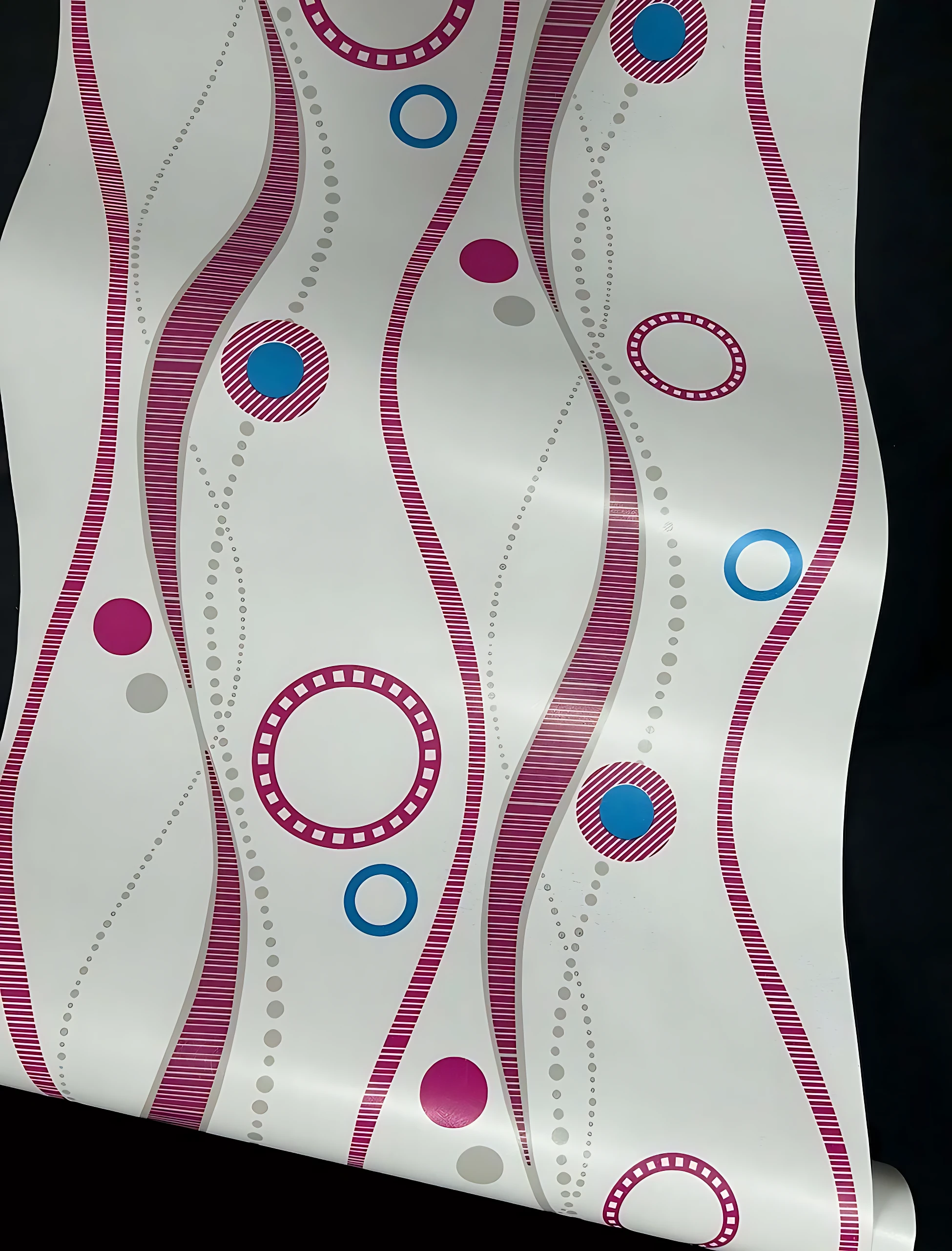 Papel adhesivo decorativo con diseño geométrico en líneas onduladas rosas y círculos azules sobre fondo blanco, ideal para renovar paredes sin obras.