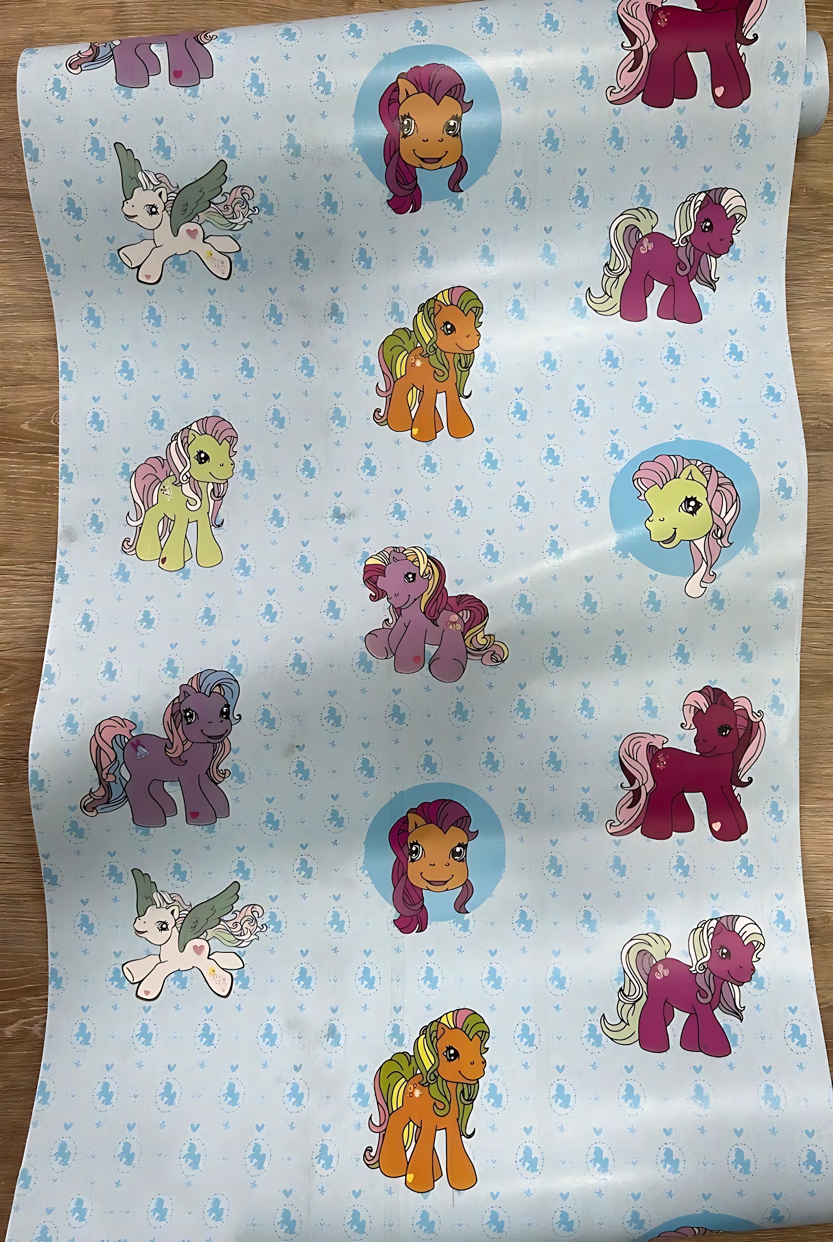 Papel adhesivo decorativo infantil con personajes de My Little Pony sobre fondo azul claro con patrones de nubes.