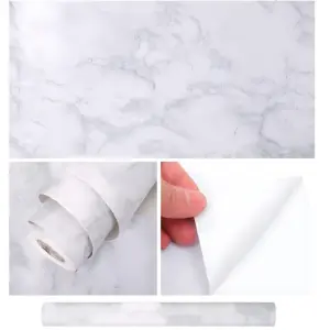 Papel adhesivo decorativo marmolado blanco con vetas grises, mostrando textura, aplicación y rollo completo.