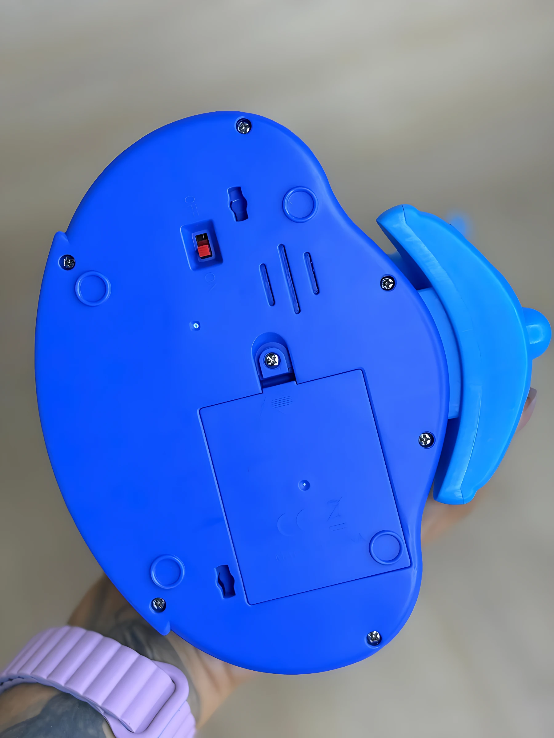 Vista inferior del piano educativo Stitch 818 en color azul, mostrando compartimento para pilas, tornillos de fijación y soporte lateral.