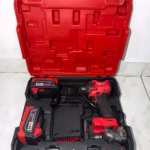 Caja abierta de color rojo con herramientas inalámbricas Milwaukee: pistola de impacto, dos baterías recargables y cargador, dispuestas en compartimentos organizados.