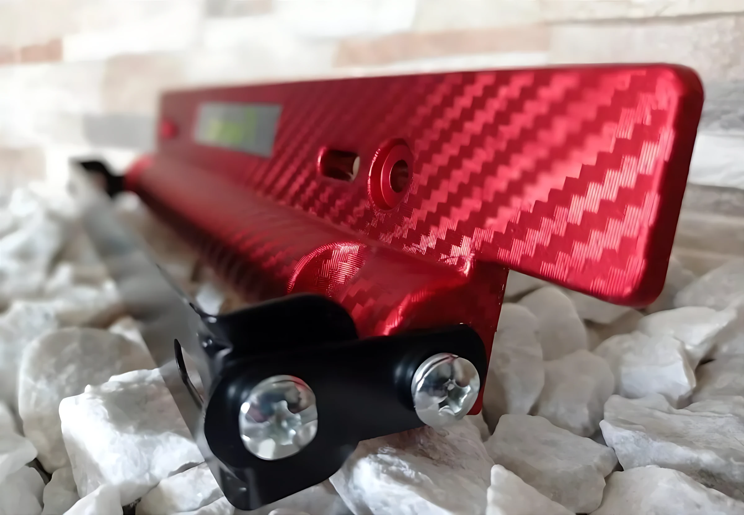 Porta placa fibra carbono rojo con platina metálica, diseño deportivo para montaje de matrícula en vehículos.