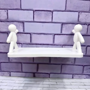 Repisa blanca con dos figuras humanas de estilo minimalista, montada sobre pared de ladrillo pintado en tono lila.