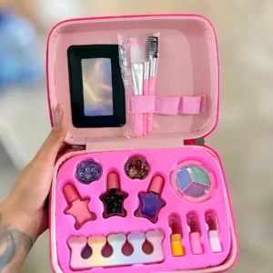 Maleta de maquillaje rosa con espejo, brochas, labiales en forma de estrellas y paleta de colores.