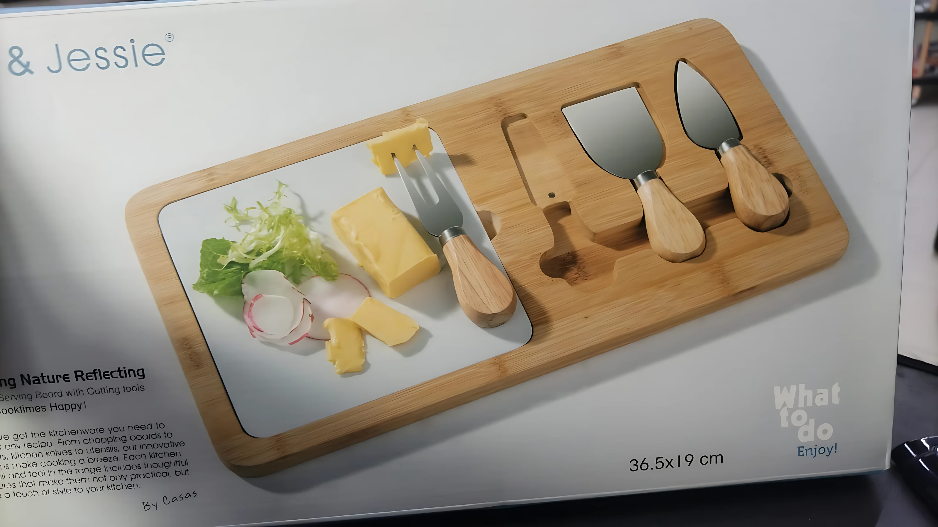 Tabla de queso cuadrada de madera clara con superficie blanca, incluye cuatro herramientas de corte con mangos de madera y dimensiones de 36,5 x 19 cm.