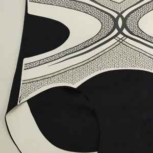 Tanga moldeadora negra con detalles blancos y estampado geométrico, vista frontal sobre superficie clara.