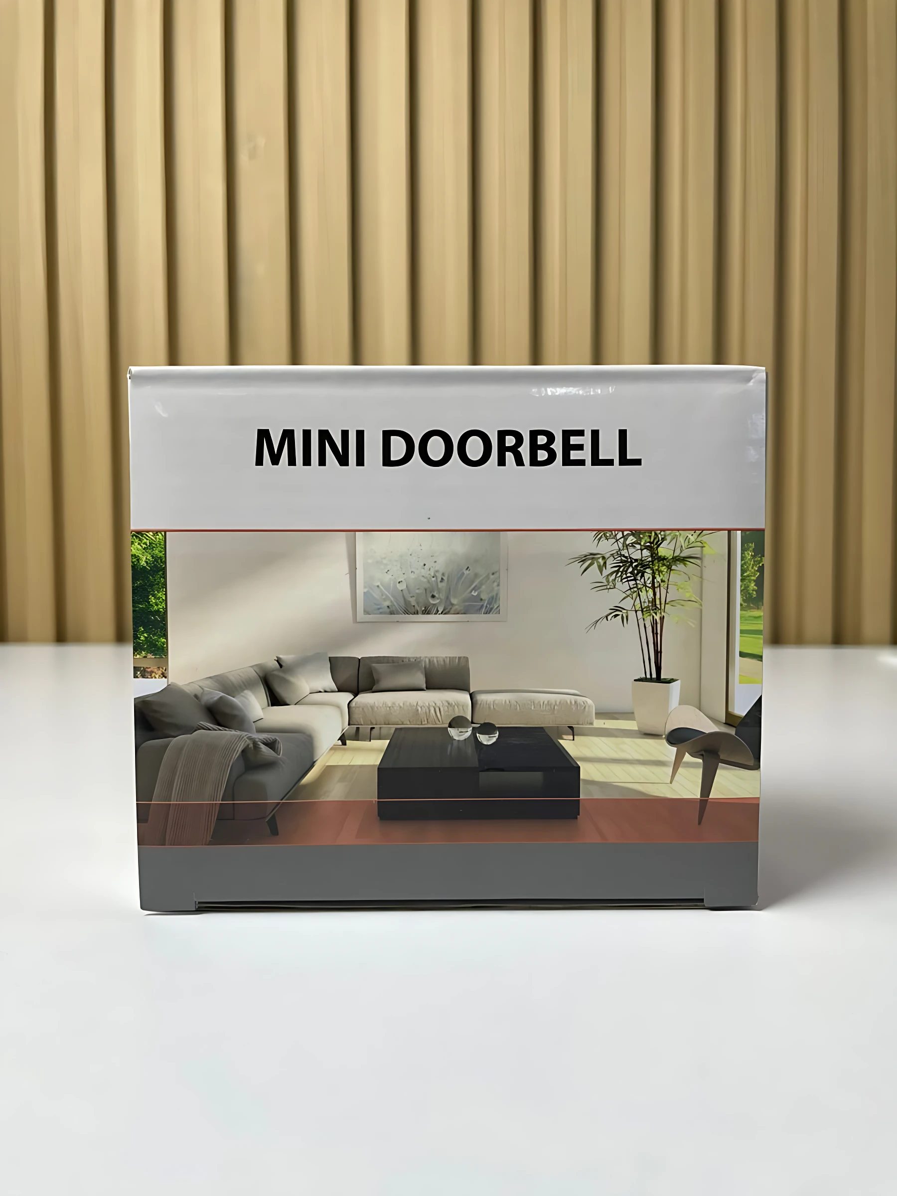 Empaque de videoportero mini doorbell con diseño de sala moderna, caja blanca y gris sobre fondo de listones beige.