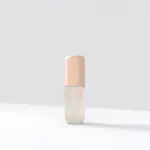 Perfume capilar Milagros Bali en frasco cilíndrico con tapa color durazno y contenido beige claro sobre fondo blanco.