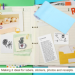 Rollo de papel térmico adhesivo color celeste para impresora portátil sobre cuaderno decorado con notas y recortes.