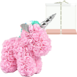Unicornio de rosas eternas rosas con cuerno plateado y corona de flores, junto a caja de regalo transparente con cinta blanca y base rosa.