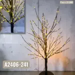 Arbusto decorativo con ramas iluminadas de luces LED cálidas junto a pared de piedra