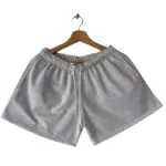 Short de dama en algodón perchado gris claro melange, con cordón blanco ajustable y bolsillos, colgado en gancho de madera.