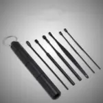 Kit de limpieza de oídos negro con estuche cilíndrico para llavero y seis herramientas con puntas y formas variadas para remover la cera.