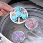 Filtro flotante para lavadora con malla blanca y bolas azules, capturando pelusas y pelos en agua con espuma.