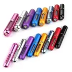 Mini atomizador de perfume portátil recargable en colores surtidos (fucsia, plateado, morado, azul, dorado, gris, rojo y negro) dispuestos en dos filas sobre fondo blanco.